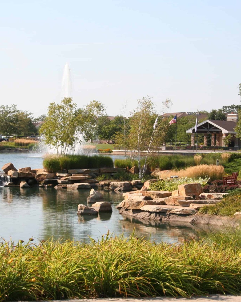 Del Webb Sun City in Huntley — landscaped lake with fountain and lodge beyond